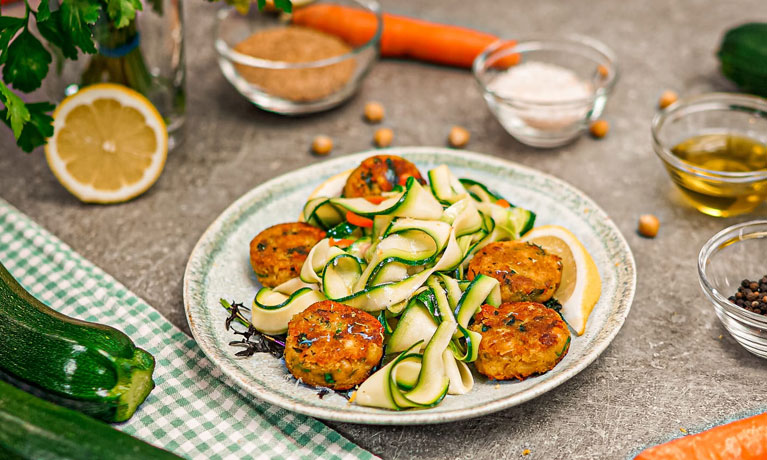 A plate with courgette salad and falafel balls.