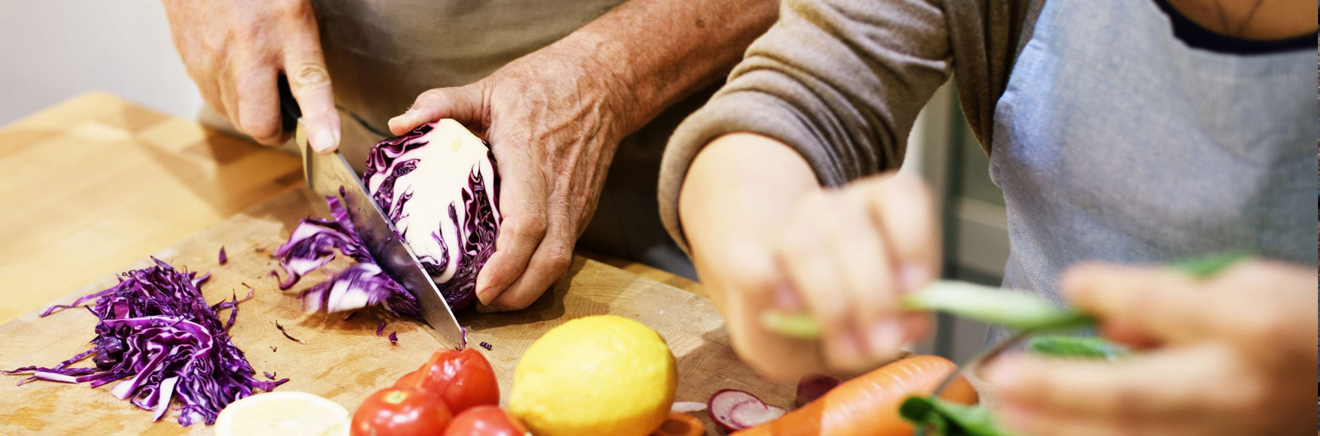 A person cutting red cabbage on a wooden board.